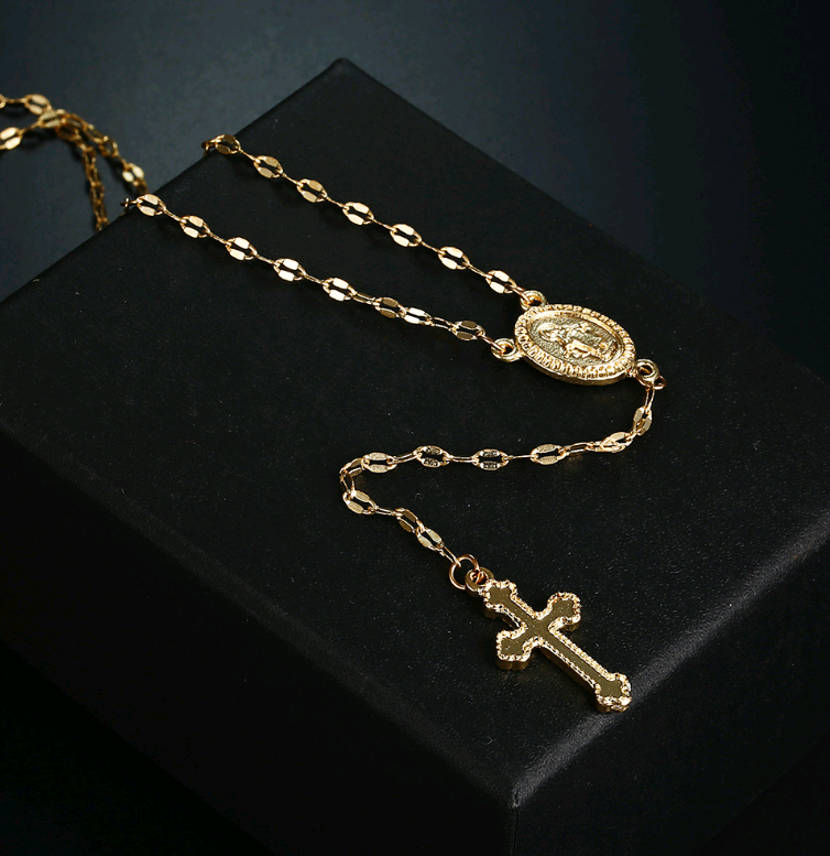 Gold necklace with a pendant and cross on a black background