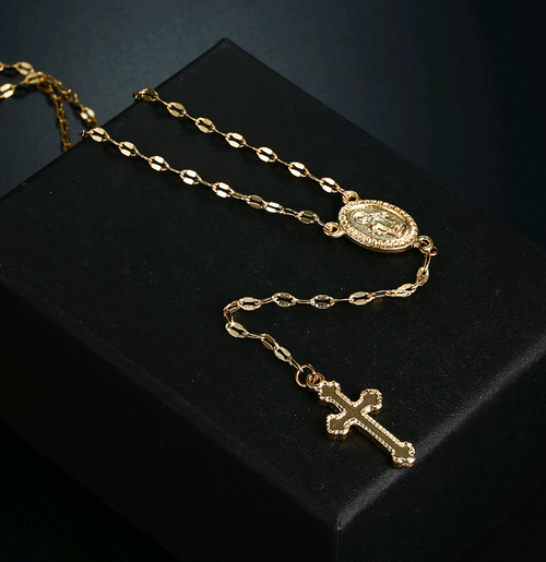 Gold necklace with a pendant and cross on a black background